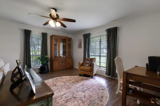 a living room with furniture a chandelier fan and a large window