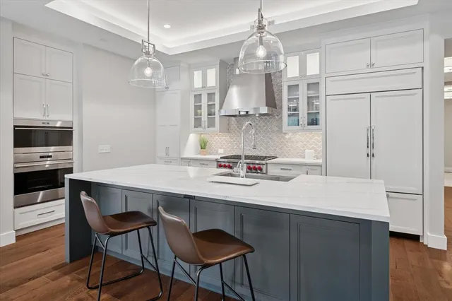a kitchen with stainless steel appliances a dining table chairs and wooden floor
