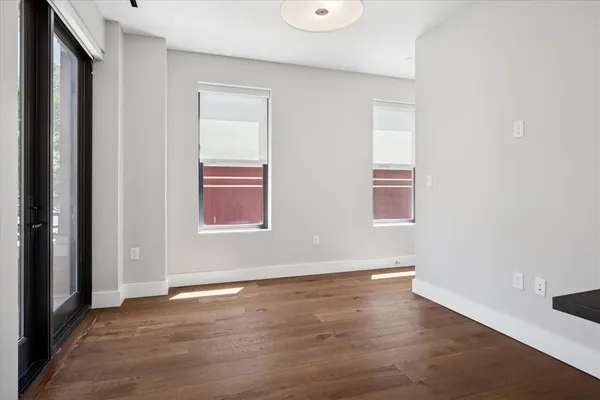 a view of an empty room with wooden floor and a window