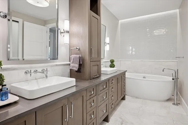 a bathroom with double vanity sinks a large mirror and a bathtub