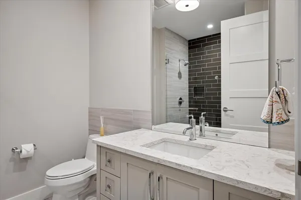 a bathroom with a granite countertop sink a toilet and a mirror
