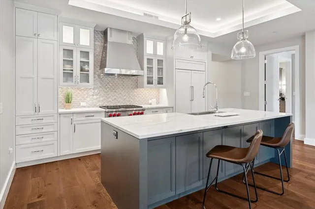 a kitchen with a stove a sink cabinets and wooden floor