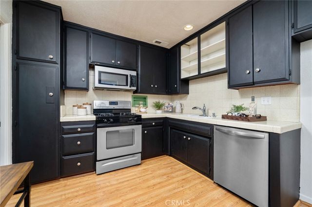 a kitchen with stainless steel appliances granite countertop a refrigerator a stove a sink dishwasher and wooden cabinets with wooden floor