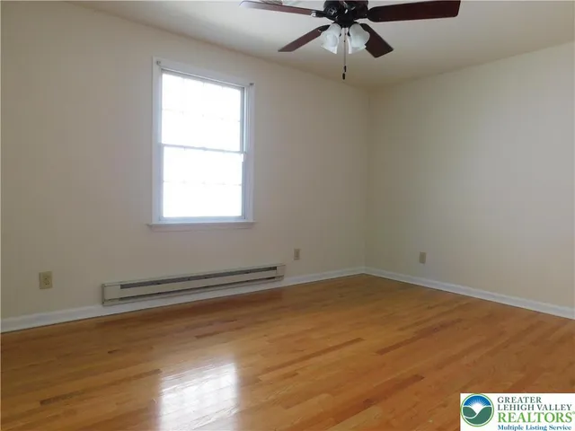 an empty room with wooden floor and ceiling fan