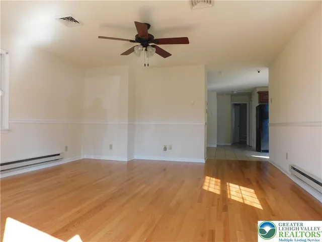 a view of empty room with wooden floor and fan