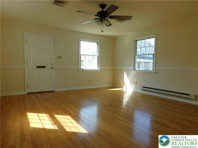 a view of empty room with wooden floor and fan