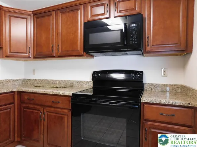a kitchen with granite countertop a stove and a microwave