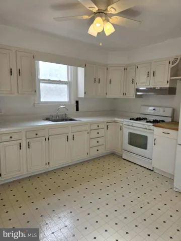 a kitchen with a sink a stove cabinets and a window