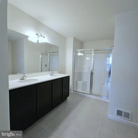 a bathroom with a double vanity sink mirror and shower