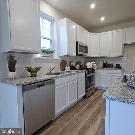 a kitchen with granite countertop a sink a stove and cabinets