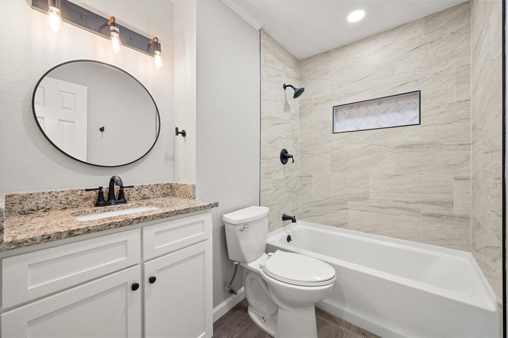 1009 North Spikes Road Corsicana, TX 75110 - Photo 11 of 31 a bathroom with a granite countertop toilet a sink and a bathtub