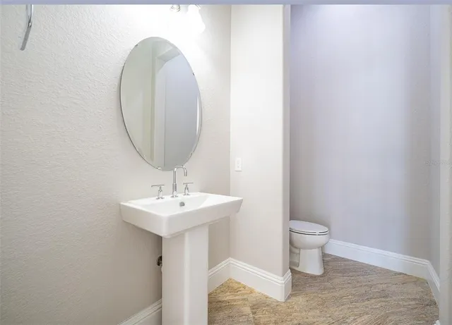 a large kitchen with stainless steel appliances granite countertop a stove a sink a refrigerator and white cabinets with wooden floor