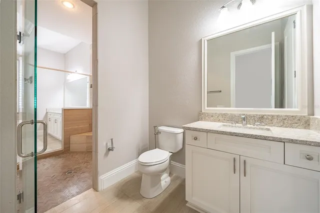 a bathroom with a granite countertop bathtub shower sink vanity and toilet