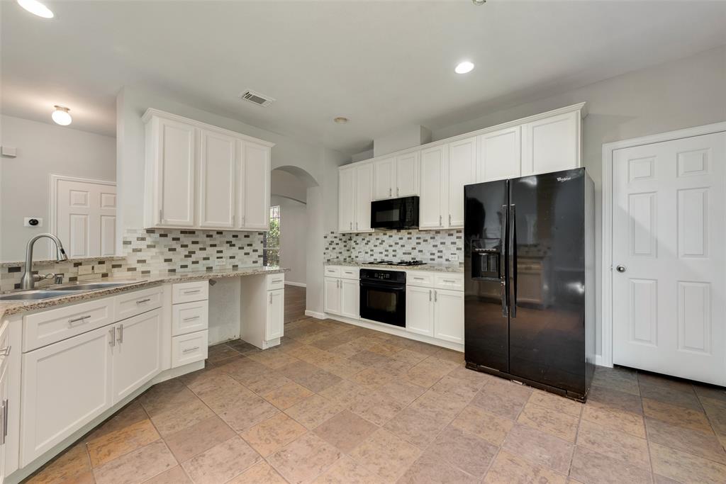 2716 Raspberry Court Plano, TX 75074 - Photo 8 of 20 Kitchen with black appliances, sink, white cabinetry, light stone counters, and decorative backsplash
