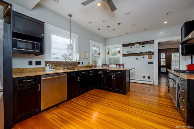 a kitchen with stainless steel appliances kitchen island granite countertop a refrigerator a sink dishwasher a stove and white cabinets with wooden floor