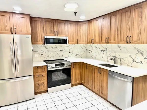a kitchen with granite countertop a refrigerator stove top oven and cabinets