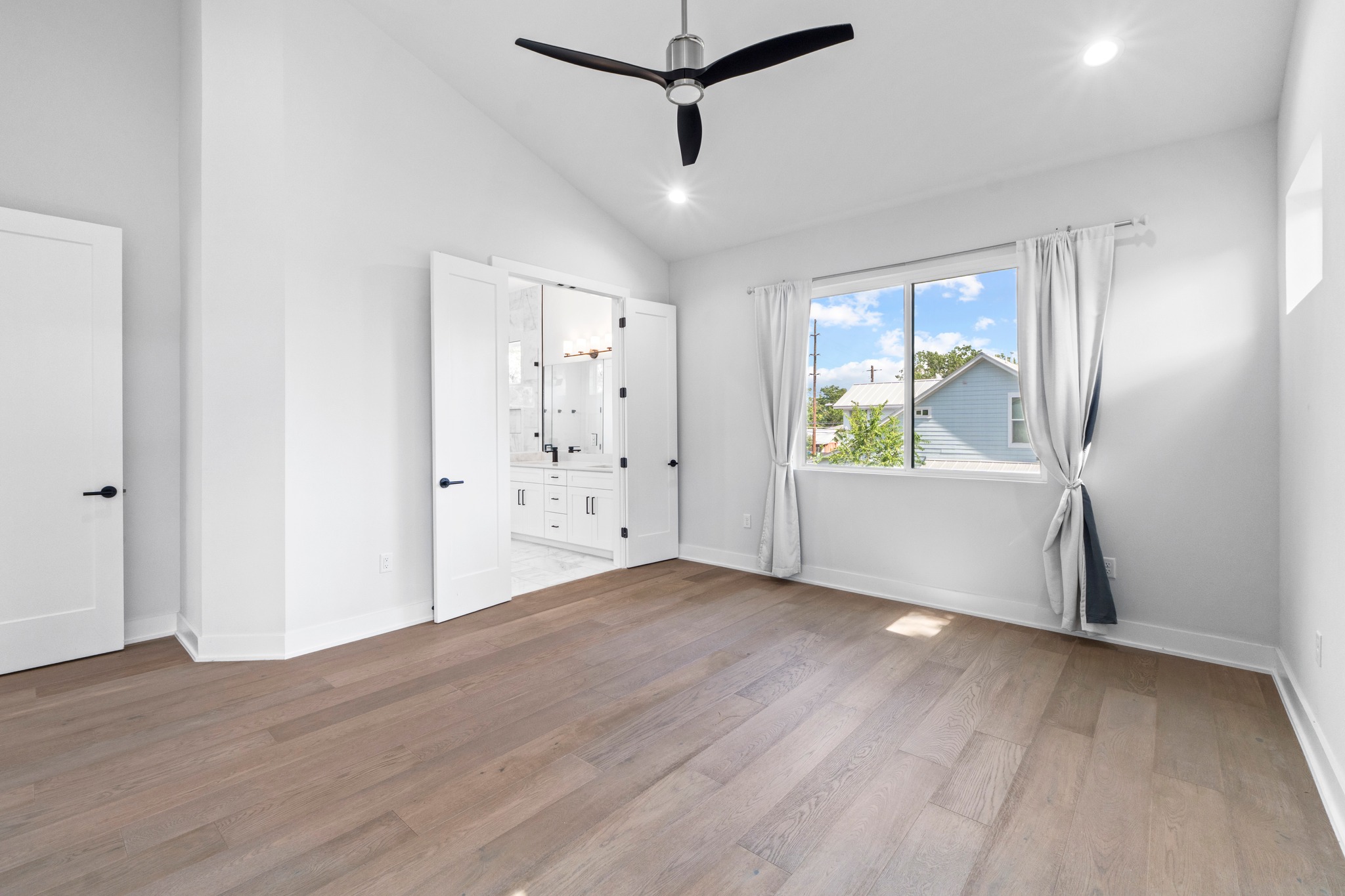 2007 Chestnut Avenue, Unit 1 Austin, TX 78722 - Photo 21 of 32 A well-lit primary bedroom offers high ceilings and attractive wood flooring, with a private bathroom entry.