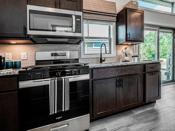 a kitchen with stainless steel appliances granite countertop a stove a sink and a microwave