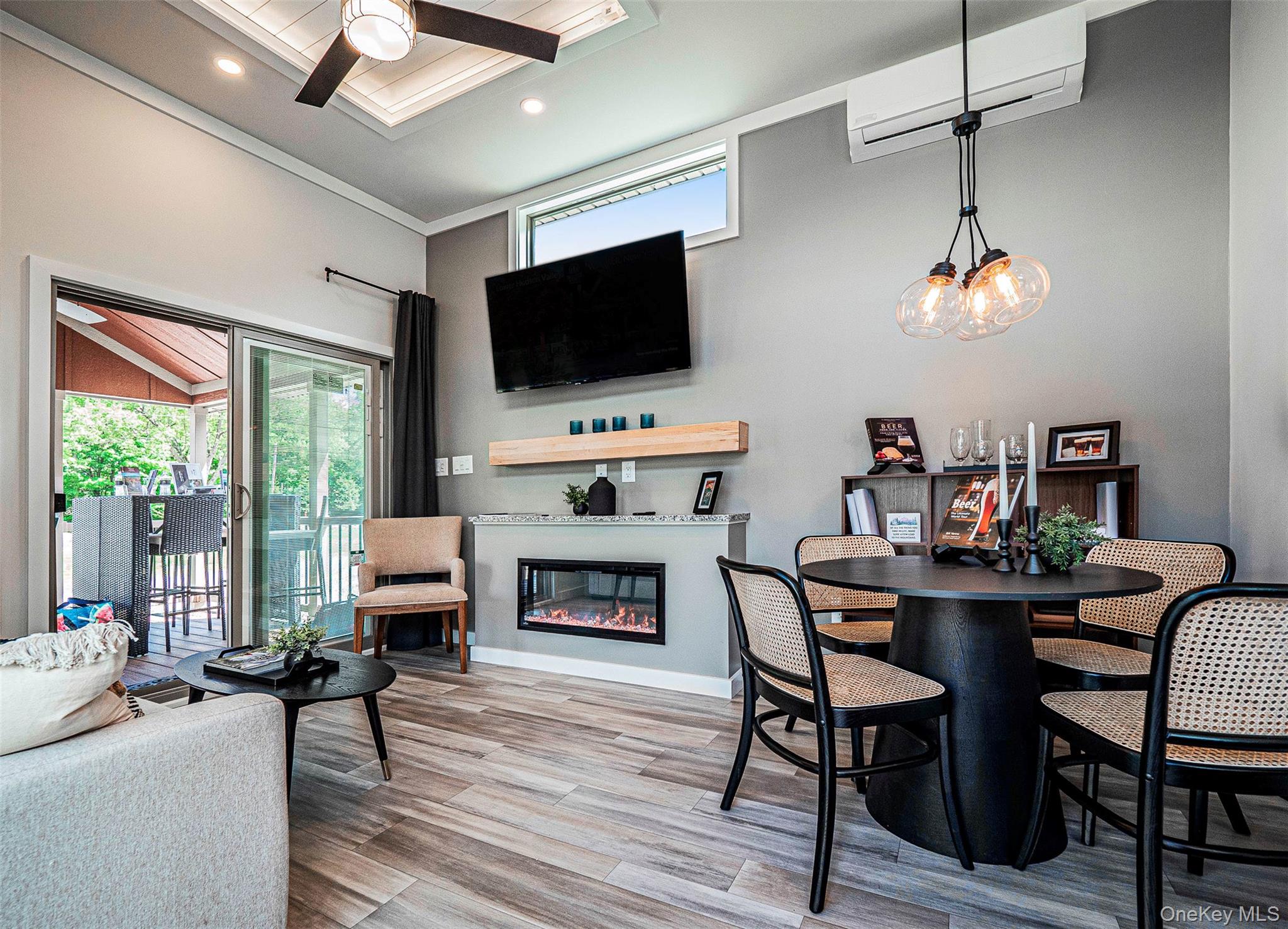 197 Wheeler Road, Unit 101 Florida, NY 10921 - Photo 6 of 41 Dining space featuring a wall mounted AC, a glass covered fireplace, LVP flooring, a ceiling fan, and ornamental molding