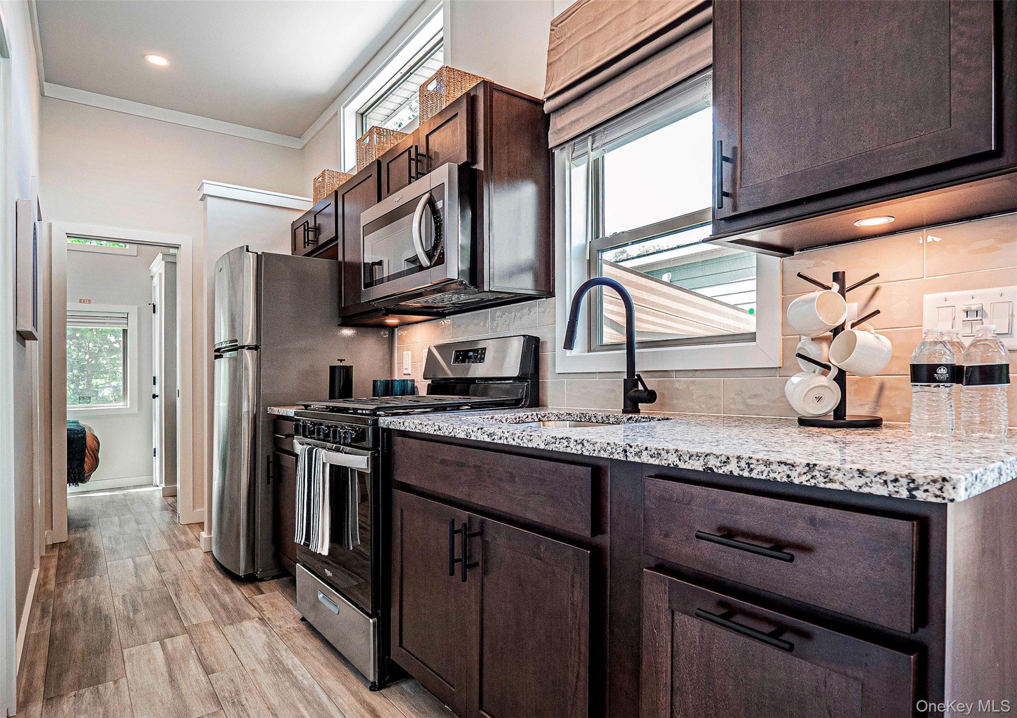 197 Wheeler Road, Unit 101 Florida, NY 10921 - Photo 9 of 41 Kitchen featuring stainless steel appliances, dark brown cabinets, plenty of natural light, ornamental molding, and light wood-type flooring