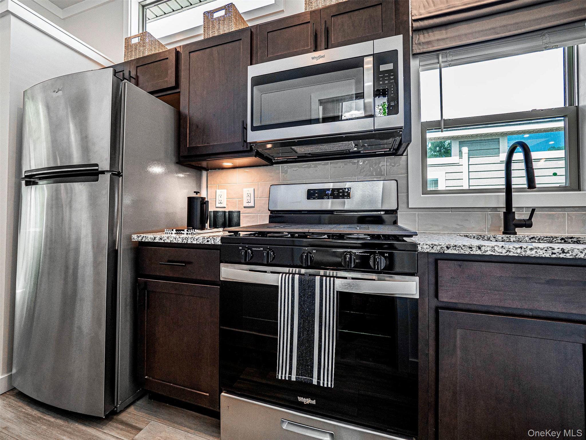 197 Wheeler Road, Unit 101 Florida, NY 10921 - Photo 10 of 41 Kitchen featuring appliances with stainless steel finishes, dark brown cabinetry, decorative backsplash, and light wood-type flooring
