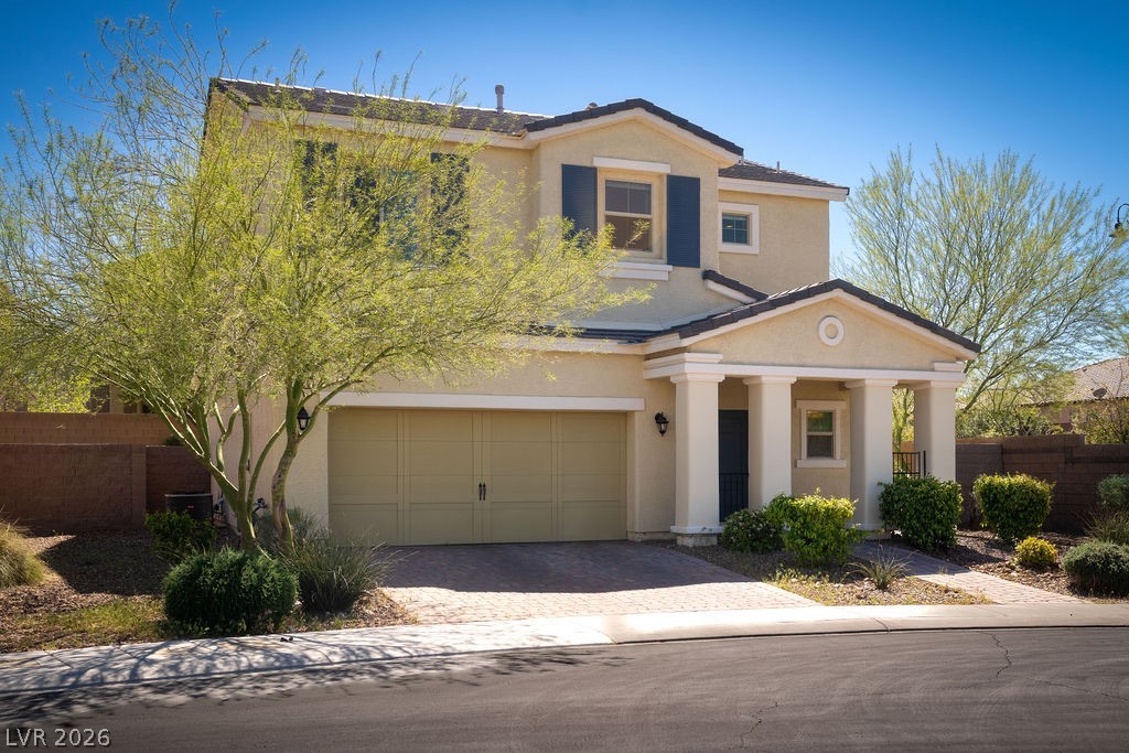Two-story Inspirada home on a quiet cul-de-sac — freshly maintained stucco, decorative paver driveway, and a mature palo verde tree framing the front elevation. The blue shutters and covered entry give this home a street presence that stands out in the neighborhood.