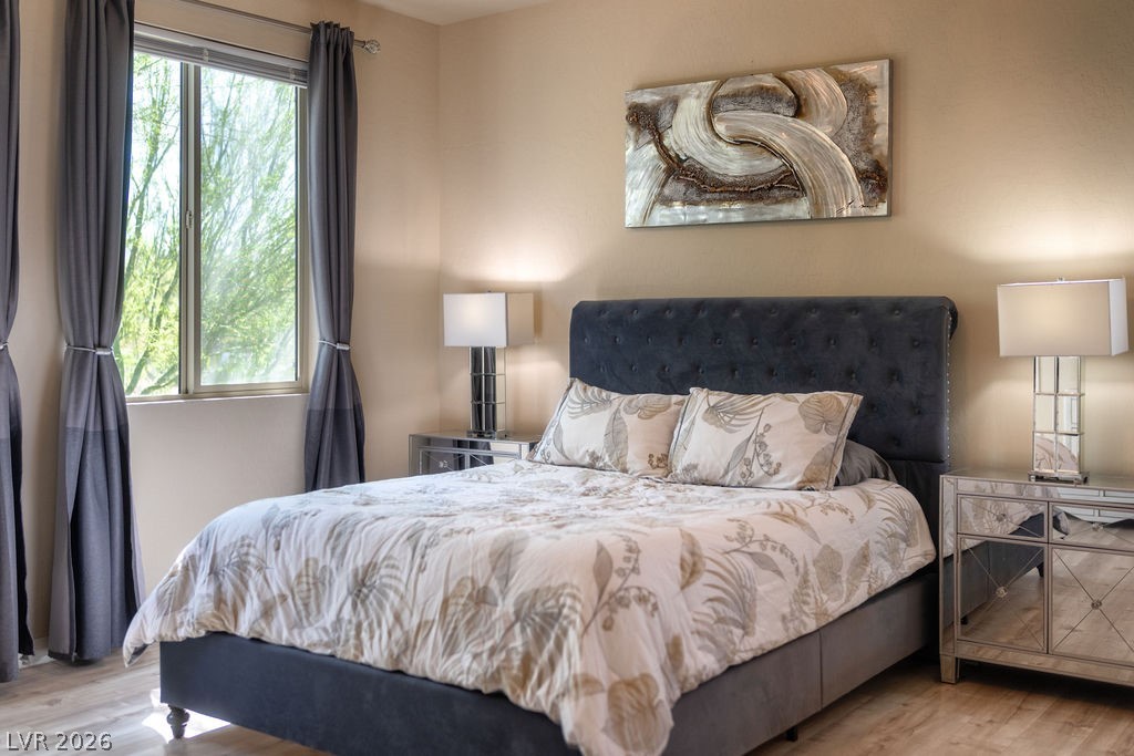 3069 Scenic Rhyme Avenue Henderson, NV 89044 - Photo 13 of 29 The tufted navy headboard, mirrored nightstands, and layered bedding show what this bedroom feels like when it's yours. The treetop views through the window are part of the daily experience here.
