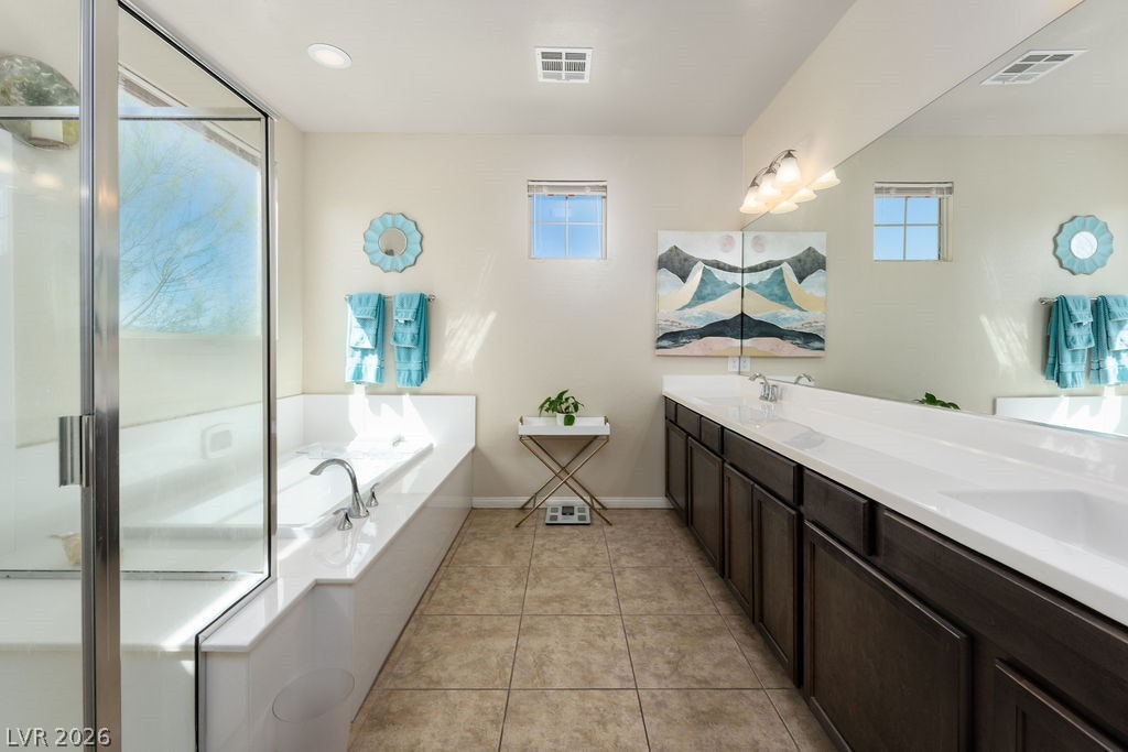 3069 Scenic Rhyme Avenue Henderson, NV 89044 - Photo 15 of 29 The primary suite bathroom delivers the full package in one room: soaking tub with a picture window above, separate glass-enclosed shower, and a long dual vanity with dark wood cabinetry and white countertops. Every morning feels different in here.
