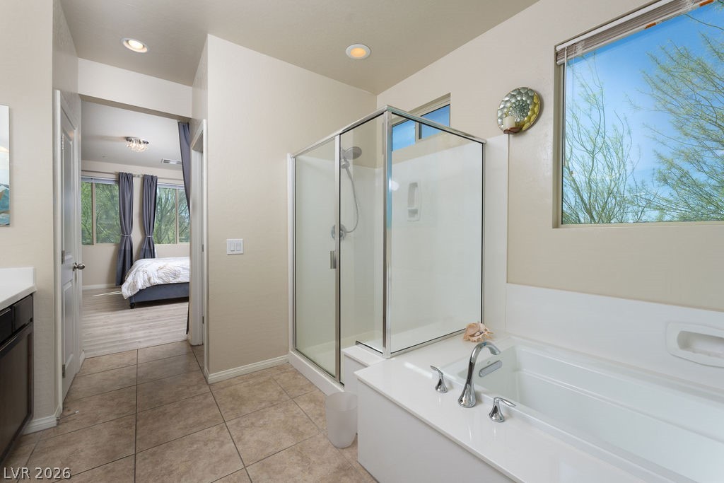 3069 Scenic Rhyme Avenue Henderson, NV 89044 - Photo 16 of 29 Looking from the shower back toward the soaking tub and the doorway to the primary suite — the bath and bedroom connect as a true suite. The glass enclosure and natural light keep the space bright and open.