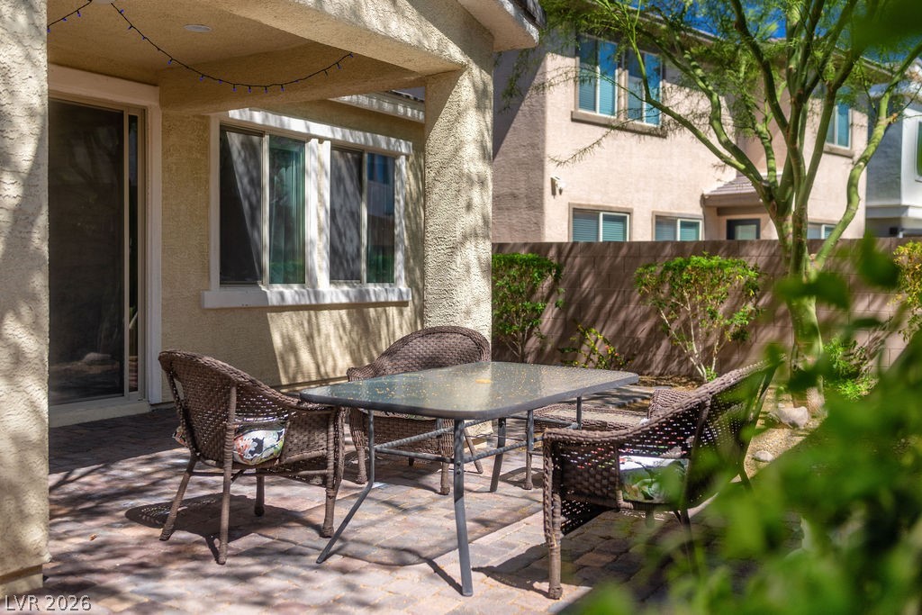 3069 Scenic Rhyme Avenue Henderson, NV 89044 - Photo 20 of 29 A wicker dining set under the covered patio, with string lights overhead and desert plantings along the wall. In Las Vegas, a shaded outdoor dining space isn't a luxury — it's the difference between using your backyard nine months a year or three.