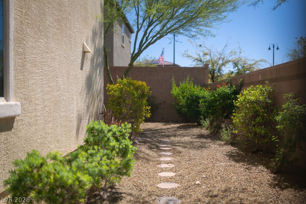 3069 Scenic Rhyme Avenue Henderson, NV 89044 - Photo 21 of 29 A stepping-stone path winds through a thoughtfully planted side yard with desert-adapted shrubs and flowering plants. Low water, low maintenance, and it actually looks like something — not just gravel and a wall.