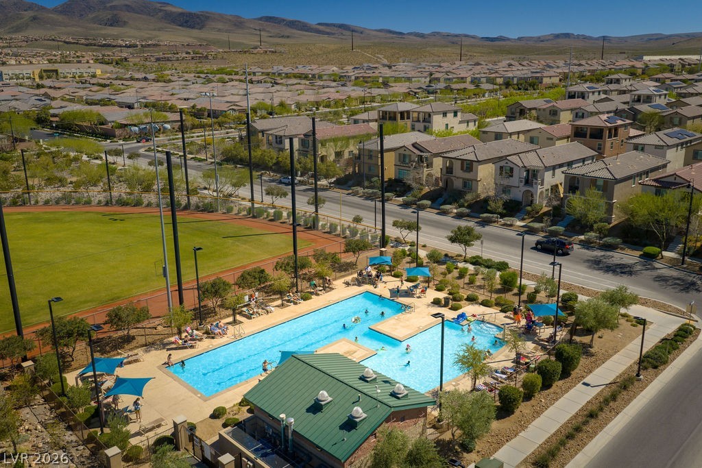 3069 Scenic Rhyme Avenue Henderson, NV 89044 - Photo 23 of 29 The Inspirada community pool on a busy afternoon — chaise lounges, shade umbrellas, families in the water, and the Spring Mountains rising behind the pool deck. A short walk from the front door, maintained by the HOA, available every day of the year.