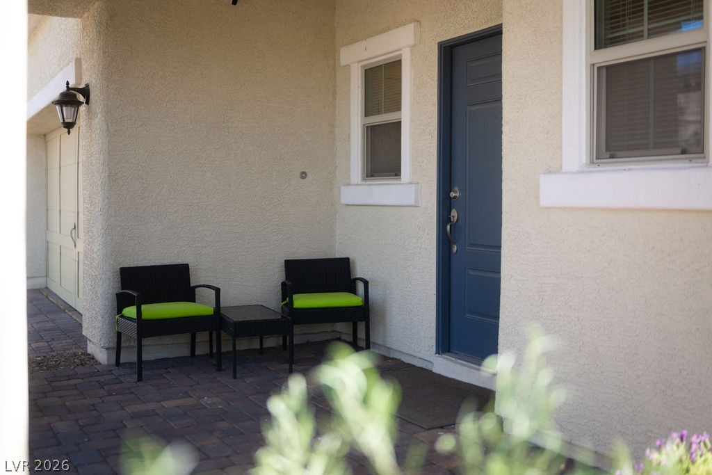 3069 Scenic Rhyme Avenue Henderson, NV 89044 - Photo 3 of 29 The covered front porch with its bold blue entry door and paired sconce lighting is the kind of detail that makes a house feel like a home before you've stepped inside. Already set up for a morning coffee routine — and it fits.