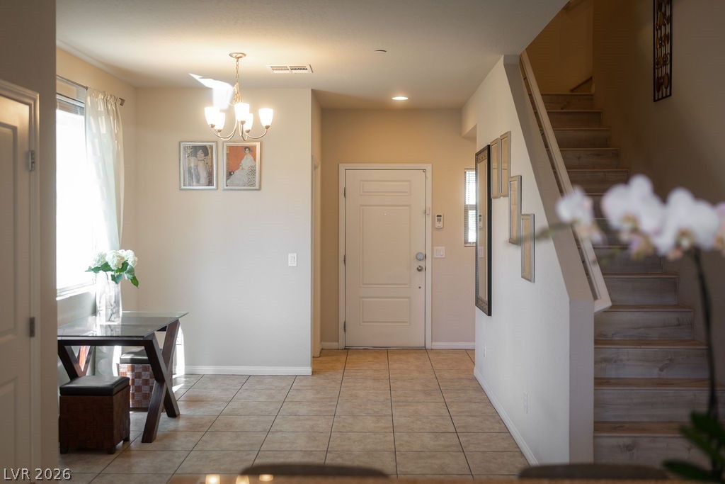 3069 Scenic Rhyme Avenue Henderson, NV 89044 - Photo 7 of 29 A well-lit entry zone with 9' ceilings, a five-arm chandelier, and large-format tile flooring running through the entire main level. The gallery wall and dedicated dining nook signal this is a home that was set up to be lived in — not just listed.