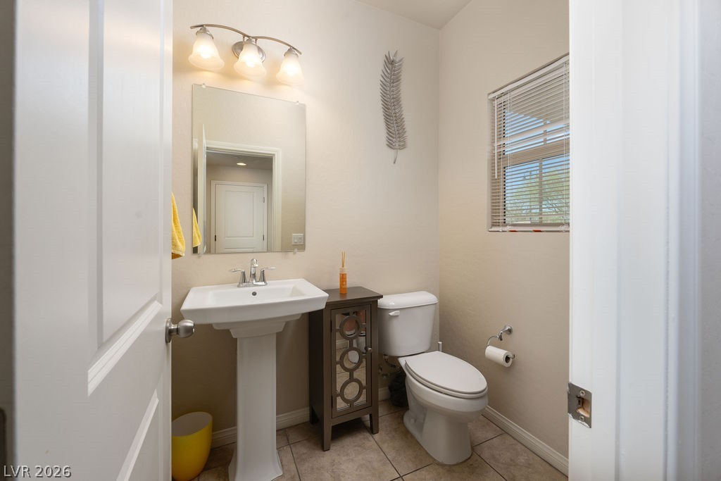 3069 Scenic Rhyme Avenue Henderson, NV 89044 - Photo 8 of 29 A full powder room on the main level — pedestal sink, window, and chrome fixtures. Guests stay downstairs; the upstairs bathrooms stay for the household.