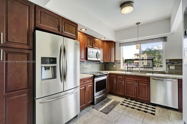 a kitchen with stainless steel appliances granite countertop a refrigerator a sink a stove and cabinets