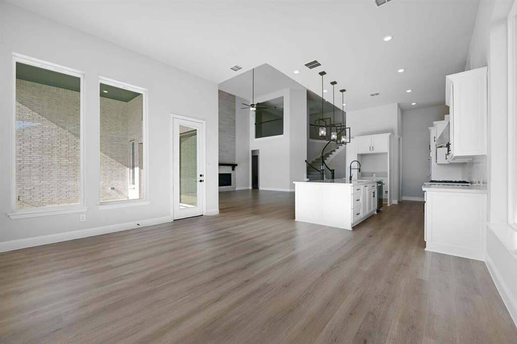 1612 Yellow Rose Road Celina, TX 75009 - Photo 9 of 40 a view of a kitchen with an empty room and wooden floor