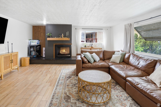 5108 South 2000th Street West Roy, UT 84067 - Photo 3 of 61 Living room with light wood-type flooring, a fireplace, and a textured ceiling