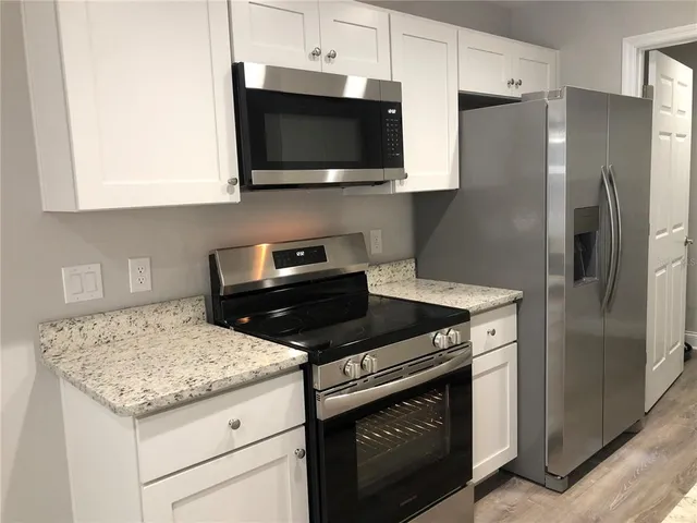 a kitchen with stainless steel appliances granite countertop a stove microwave refrigerator and sink