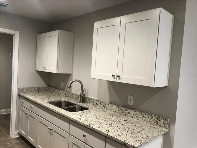 a kitchen with granite countertop white cabinets and sink
