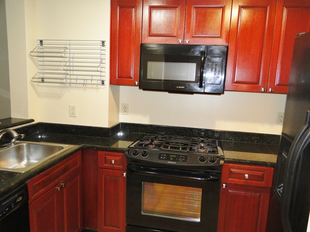 1 Nassau Street, Unit 1607 Boston, MA 02111 - Photo 6 of 17 a kitchen with granite countertop a stove and a microwave