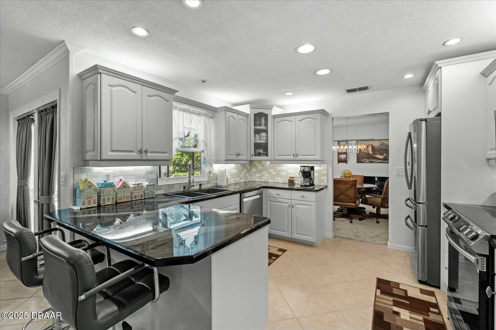 1 Cobblestone Trail Ormond Beach, FL 32174 - Photo 14 of 31 a kitchen with kitchen island granite countertop a sink cabinets and stainless steel appliances