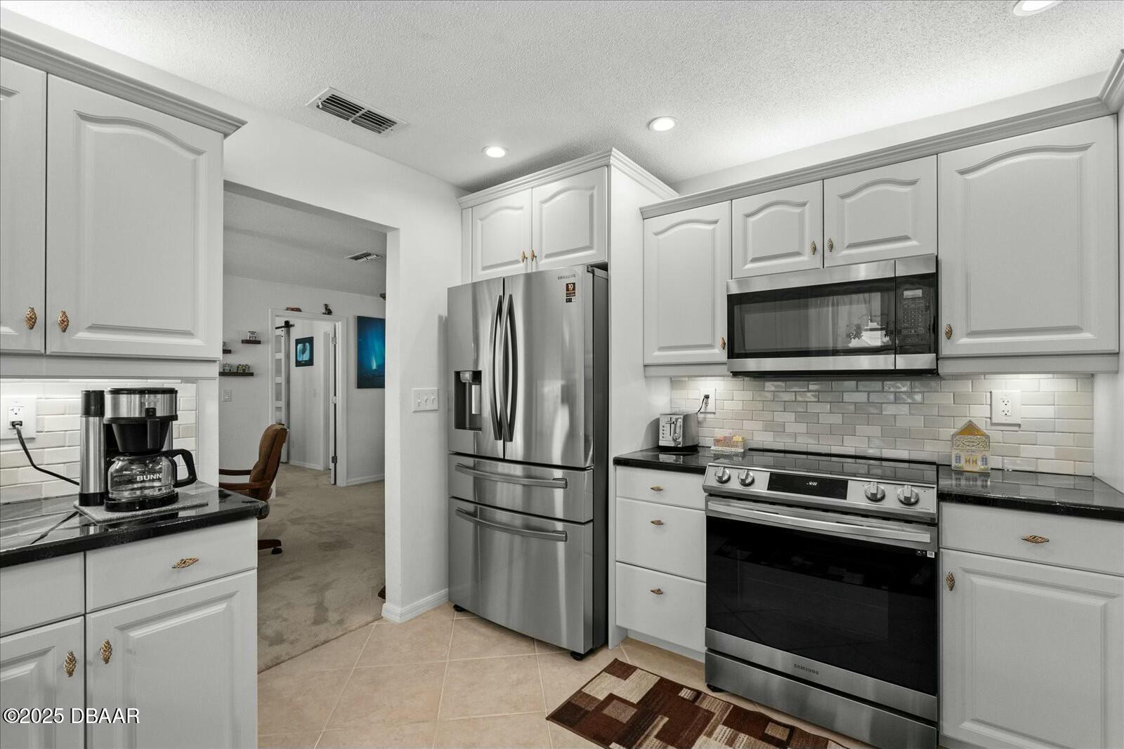 1 Cobblestone Trail Ormond Beach, FL 32174 - Photo 15 of 31 a kitchen with granite countertop a refrigerator stove and microwave