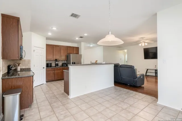 a kitchen with stainless steel appliances granite countertop a refrigerator oven a sink dishwasher and white cabinets with wooden floor