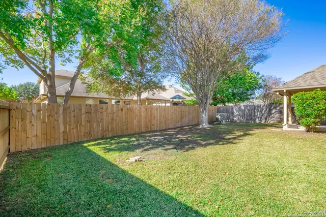 a view of a back yard with a house and large trees with wooden fence