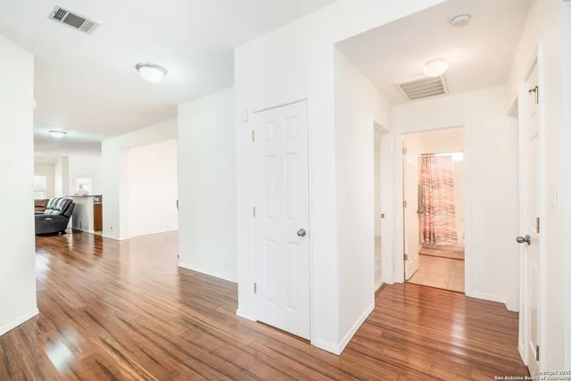 a view of a hallway with wooden floor a glass table and chairs