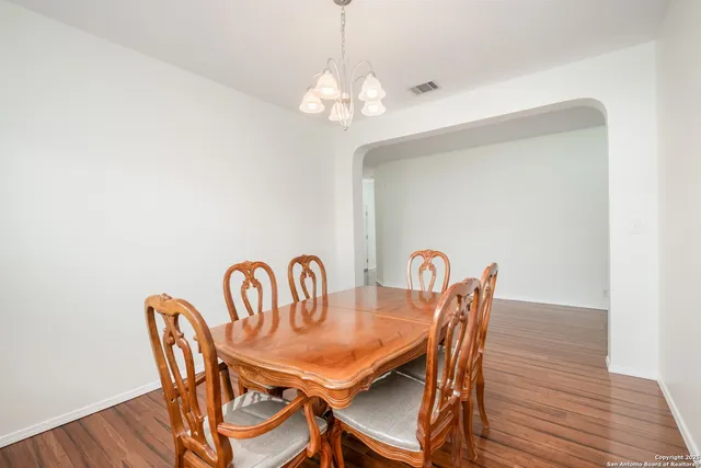 a dining room with furniture a chandelier and wooden floor