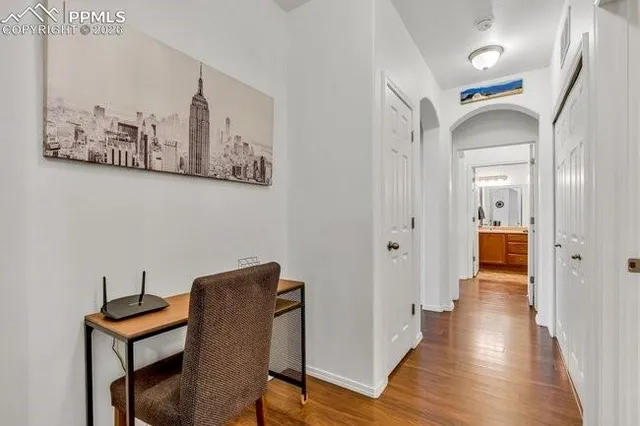 a view of a hallway with wooden floor and a workspace