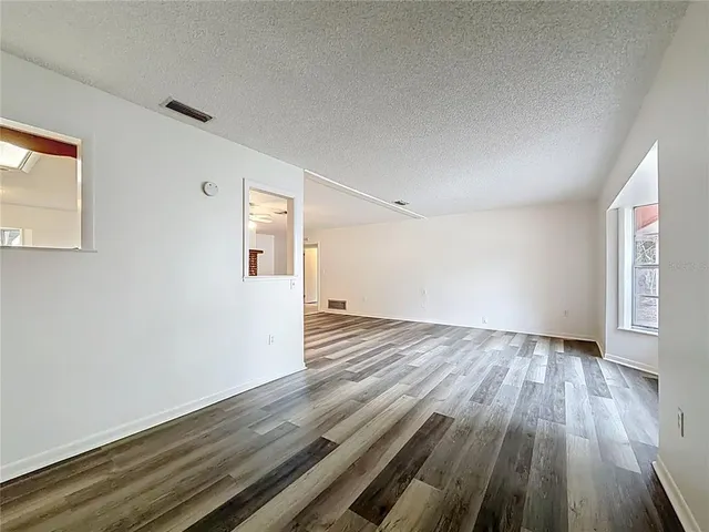an empty room with wooden floor a fireplace and windows