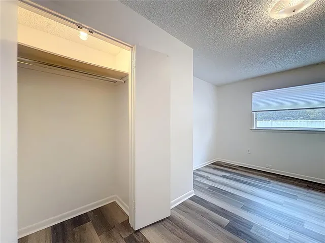 an empty room with wooden floor ceiling fan and windows